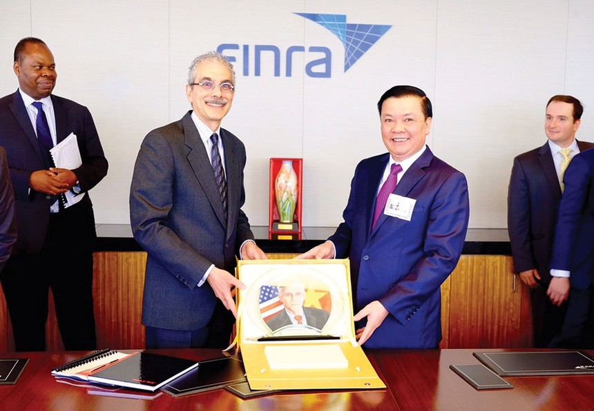 Bộ trưởng Đinh Tiến Dũng tặng quà cho Tổ chức Finra, Tổ chức giữ gìn sự liêm chính trên thị trường chứng khoán Mỹ, trong chuyến xúc tiến đầu tư tại New York, tháng 7/2015 