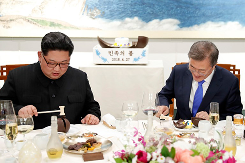Ông Kim và ông Moon dùng búa nhỏ đập vỡ món bánh có bản đồ bán đảo Triều Tiên trên bàn tiệc. Ảnh: AFP 