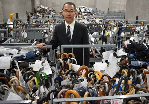 Ông Shoji Okubo, giám đốc trung tâm xử lý đồ thất lạc của Sở cảnh sát Tokyo, đứng giữa những chiếc ô vô chủ. Ảnh: Japan Times 