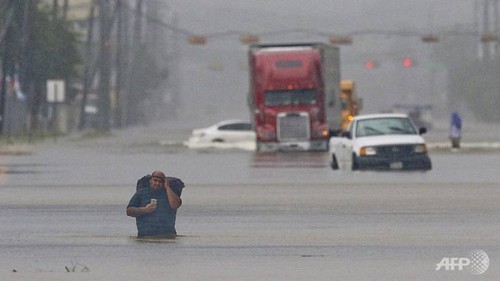 Một người đàn ông, vác theo đồ đạc trên lưng, lội qua đoạn ngập nước trên phố Telephone ở thành phố Houston, bang Texas, Mỹ vào ngày 27/8. Ảnh: AFP.