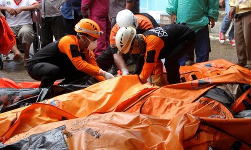 Lực lượng cứu hộ Indonesia bên cạnh túi đựng thi thể nạn nhân sáng 24/12. Ảnh: AFP.