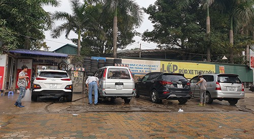 Tiệm rửa xe báo giá 200.000 đồng một lần rửa ôtô, song vẫn kín khách với nhiều người ngồi chờ trong sáng ngày 29 Tết. Ảnh: Minh Châu