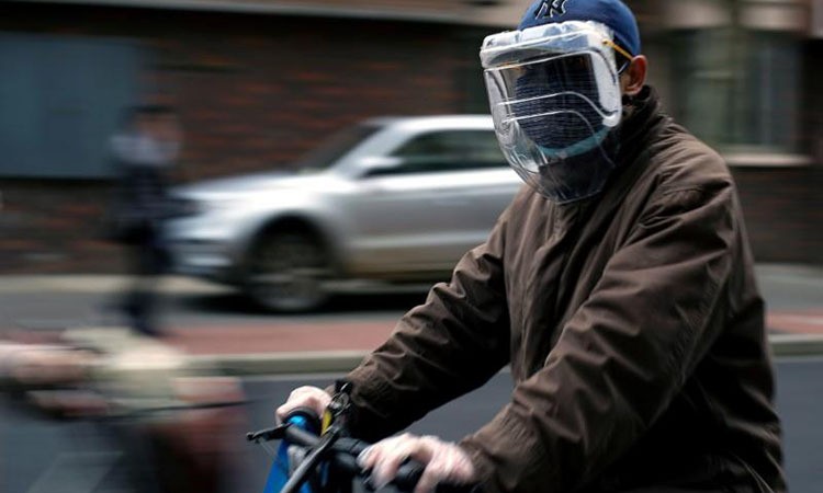 Một người dân đeo khẩu trang và mặt nạ tự chế từ chai nhựa trên đường phố Thượng Hải, Trung Quốc hôm 22/3. Ảnh: Reuters.