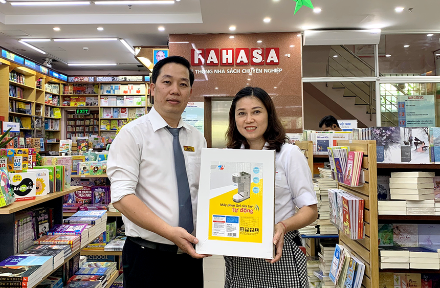 Đại diện nhà sách Fahasa Tân Bình (bên trái) nhận Máy phun gel rửa tay tự động từ đại diện công ty Thiên Long Hoàn Cầu – công ty thành viên của Tập đoàn Thiên Long.