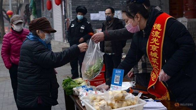 Nhân viên đứng bán tại sạp hàng dựng tạm trước cửa một trung tâm thương mại ở Bắc Kinh