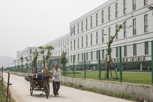 Một người đàn ông đang kéo một chiếc xe kéo phía trước nhà máy được điều hành bởi Tập đoàn Công nghệ Quang học Sunny. (Nguồn: Qilai Shen/Bloomberg).