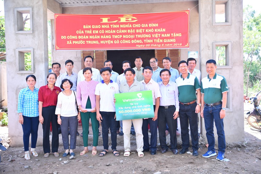 Gia đình ông Huỳnh Văn Được cùng đại diện Vietcombank và lãnh đạo địa phương chụp ảnh lưu niệm bên ngôi nhà mới.