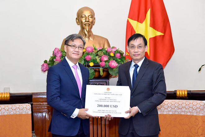 Thứ trưởng Lê Hoài Trung (phải) trao số tiền ủng hộ thông qua đại sứ Lào tại Việt Nam Thongsavanh Phomvihane. Ảnh: Bộ Ngoại giao.