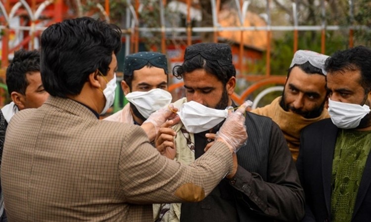 Tình nguyện viên Afghanistan phát khẩu trang tại Herat, nằm sát biên giới Iran ngày 26/2. Ảnh: AFP.