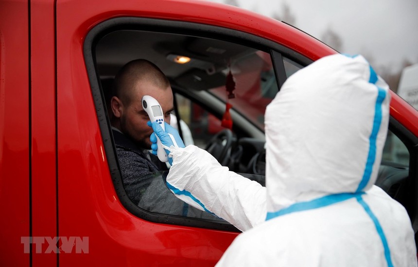 Nhân viên y tế kiểm tra thân nhiệt một lái xe tại khu vực cửa khẩu Jedrzychowice giữa Đức và Ba Lan. (Ảnh: AFP/TTXVN).