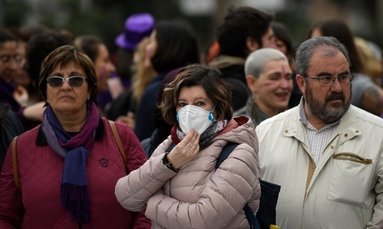 Một phụ nữ đeo khẩu trang giữa những người không có dụng cụ bảo hộ nào tại sự kiện kỷ niệm Ngày Quốc tế Phụ nữ 8/3 ở Madrid, Tây Ban Nha. Ảnh: AFP.