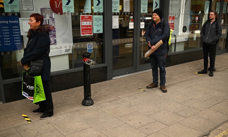 Người dân xếp hàng ngoài một hiệu thuốc tại thủ đô London hôm 30/3. Ảnh: AFP.