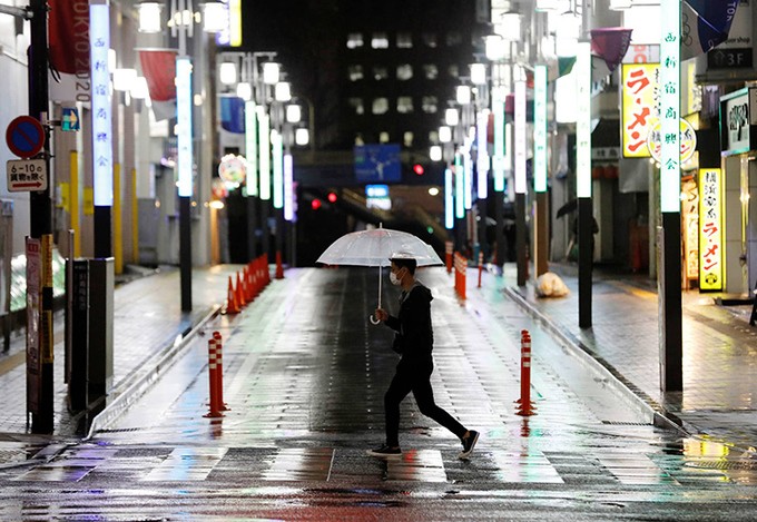 Nam thanh niên đi qua một đường phố Tokyo vắng vẻ hôm 16/4. Ảnh: Reuters.