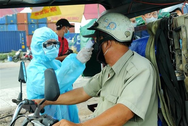 Nhân viên y tế đo thân nhiệt người ra vào thành phố Hồ Chí Minh tại chốt kiểm dịch. (Ảnh: Đinh Hằng/TTXVN).