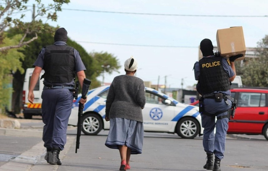 Cảnh sát Nam Phi mang hàng hóa cho một cụ già trên đường đi chợ về. (Ảnh: TTXVN phát).
