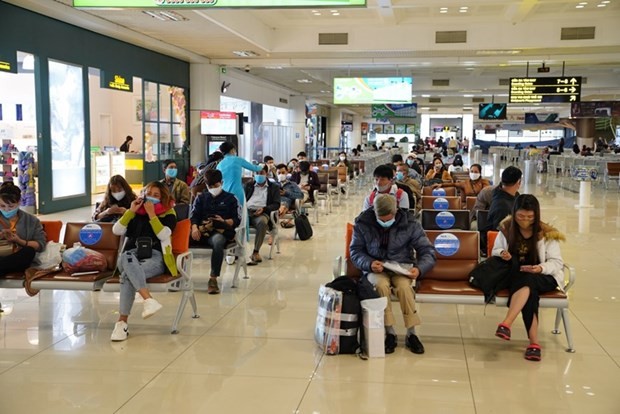 Hành khách tuân thủ giữ khoảng cách khi ngồi tại nhà ga tại sân bay Nội Bài. (Ảnh: Phan Công/Vietnam+).
