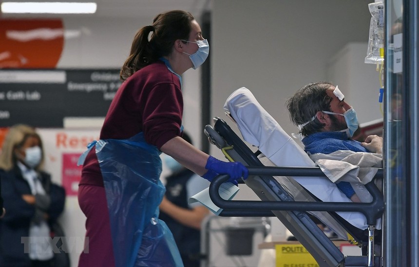 Nhân viên y tế chuyển bệnh nhân nhiễm COVID-19 tới bệnh viện ở London, Anh. (Ảnh: AFP/TTXVN).
