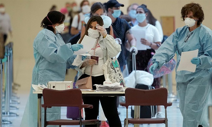 Hành khách đọc tài liệu do nhân viên y tế cung cấp khi tới sân bay Adolfo Suarez Barajas tại thủ đô Madrid, Tây Ban Nha, ngày 15/5. Ảnh: Reuters.
