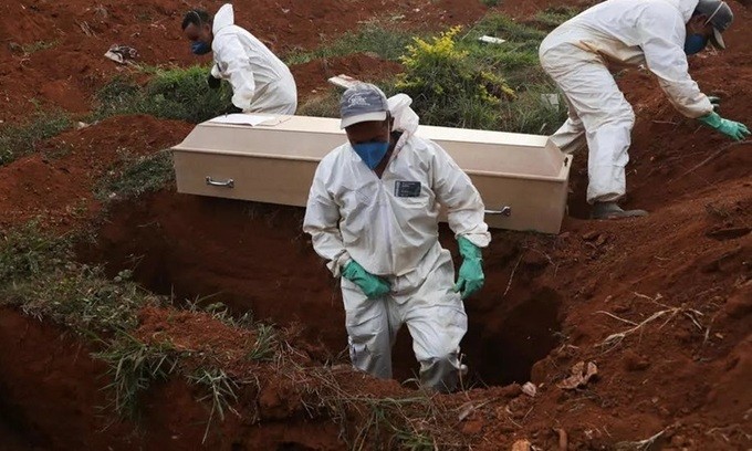 Những phu đào mộ mặc đồ bảo hộ chuẩn bị chôn cất quan tài một nạn nhân Covid-19 trong tang lễ không có người thân ở Sao Paolo, Brazil hôm 22/5. Ảnh: AFP.