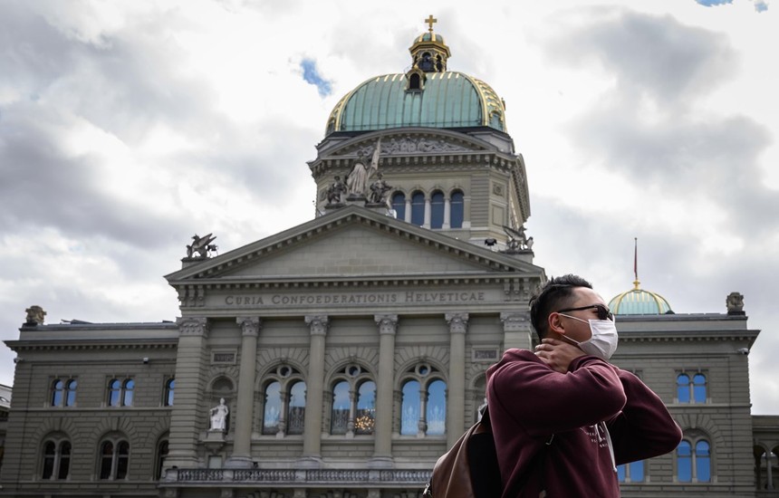 Du khách đeo khẩu trang đi ngang qua Tòa nhà Quốc hội Thụy Sĩ. (Nguồn: AFP).