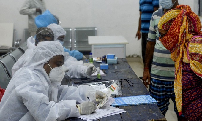 Nhân viên y tế và người dân tại một điểm sàng lọc y tế ở Mumbai, Ấn Độ, hôm 27/7. Ảnh: AFP.
