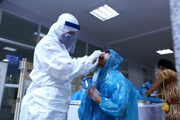 Nhân viên y tế lấy mẫu dịch hầu họng để xét nghiệm bằng phương pháp RT-PCR cho người dân trở về từ Đà Nẵng tại Trung Tâm Y Tế quận Hai Bà Trưng. (Ảnh: Minh Quyết/TTXVN).