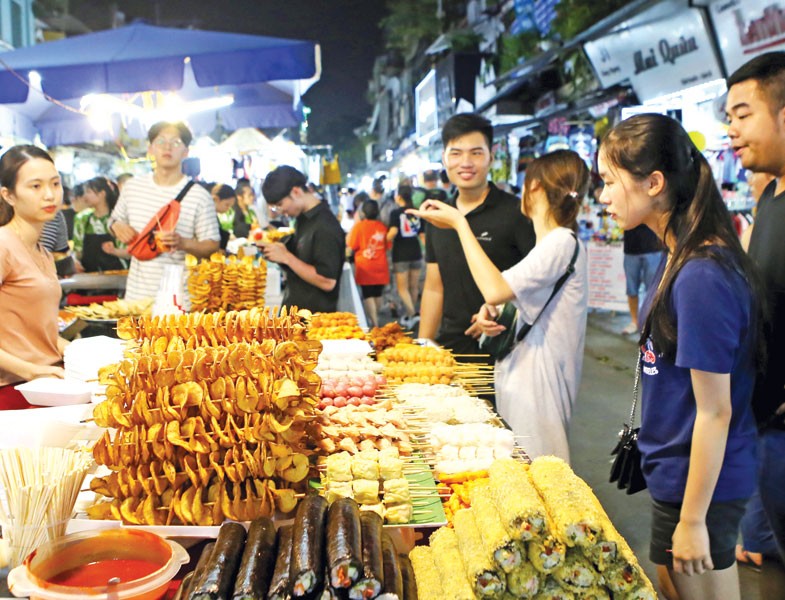 Du khách chọn món ăn tại chợ đêm khu phố cổ (quận Hoàn Kiếm, Hà Nội). Ảnh: Hồ Hạ.