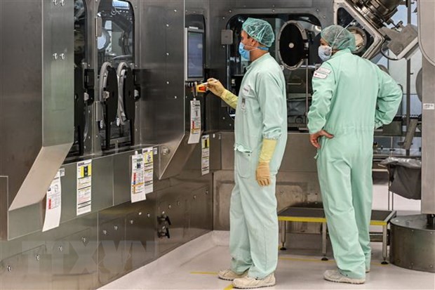 Các kỹ thuật viên giám sát việc sản xuất quy mô lớn và cung ứng vắcxin phòng COVID-19. (Ảnh: AFP/TTXVN).