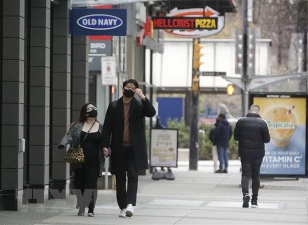 Người dân đeo khẩu trang phòng dịch COVID-19 khi đi trên đường phố ở Vancouver, British Columbia, Canada. (Ảnh: THX/TTXVN).