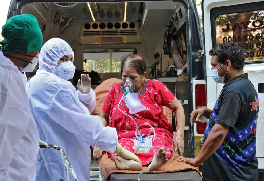 Nhân viên y tế và người thân bế một phụ nữ từ xe cấp cứu đến cơ sở điều trị Covid-19, ở Mumbai, Ấn Độ. Ảnh: Reuters.