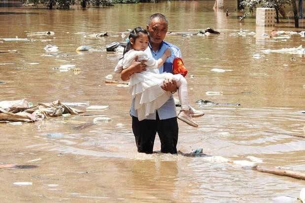 Sơ tán trẻ em khỏi khu vực bị ngập do mưa lũ. (Ảnh: AFP/TTXVN).