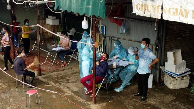 Lực lượng chức năng lấy mẫu xét nghiệm cho các tiểu thương tại chợ Phùng Khoang (Ảnh: Lê Thắng).