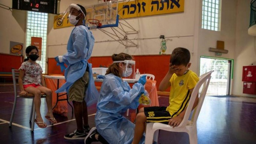 Các nhân viên y tế xét nghiệm Covid-19 cho các em nhỏ ở Binyamina, Israel. Ảnh: AP.