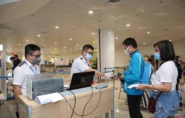 Nhân viên y tế kiểm tra phiếu khai báo y tế của hành khách trước khi làm thủ tục nhập cảnh tại cửa khẩu Sân bay quốc tế Nội Bài (Ảnh: TTXVN).