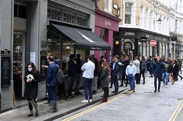 Người dân xếp hàng mua đồ bên ngoài một cửa hàng ở London (Anh), ngày 29/4/2021. (Ảnh: AFP/TTXVN).