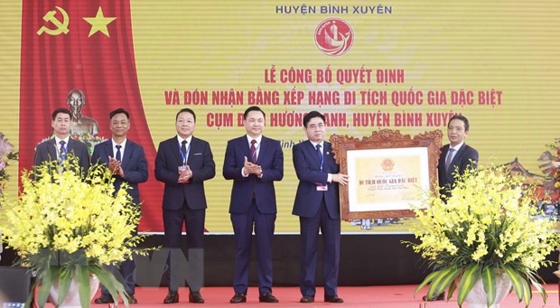 Lãnh đạo huyện Bình Xuyên (bên trái) nhận quyết định và Bằng xếp hạng di tích quốc gia đặc biệt Cụm đình Hương Canh. (Ảnh: Hoàng Hùng/TTXVN).