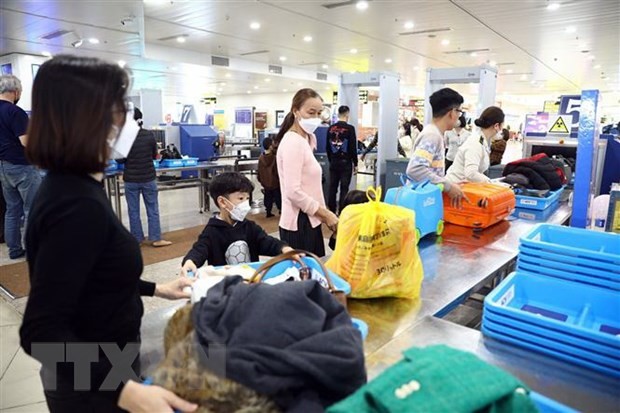 Hành khách xếp đồ để qua máy soi chiếu tại Cảng hàng không quốc tế Nội Bài. (Ảnh: Huy Hùng/TTXVN)