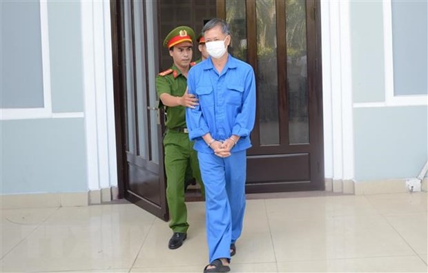 Cơ quan chức năng dẫn giải cựu Giám đốc CDC Đà Nẵng ra xe sau khi kết thúc phiên tòa sáng 25/8. (Ảnh: Văn Dũng/TTXVN)