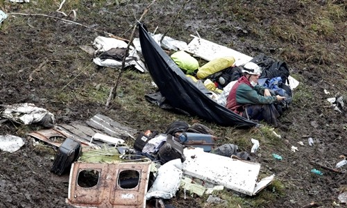 Nhân viên cứu hộ ngồi bên các mảnh vỡ của máy bay. Ảnh: Reuters