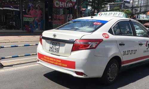 Trong hai ngày cuối tuần, hàng loạt xe taxi của hãng Vinasun treo băng rôn phản đối Grab và Uber phía sau xe. Ảnh:Hồng Nhựt.