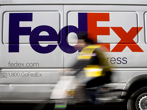 Một chiếc xe đạp lướt quaxe tải giao hàng FedEx đang đỗ tại khuMidtown,New York.Ảnh: Bloomberg.