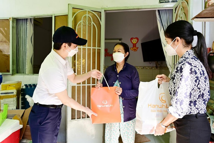Ông Bùi Quang Nam, Phó tổng giám đốc Kinh doanh Hanwha Life Việt Nam và đại diện Mặt Trận Tổ quốc Việt Nam Quận Bình Thạnh trao quà cứu trợ đến những gia đình bị ảnh hưởng bởi dịch Covid.