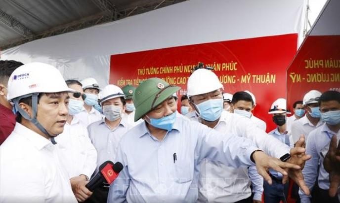 Ông Hồ Minh Hoàng (mặc áo trắng) báo cáo Thủ tướng Chính phủ Nguyễn Xuân Phúc tiến độ xây dựng đường cao tốc Trung Lương - Mỹ Thuận trong chuyến công tác thị sát Dự án vào cuối tháng 7/2020.