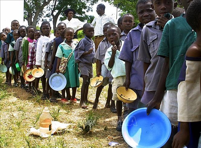 Trẻ em xếp hàng đợi nhận khẩu phần ăn do Chương trình Lương thực Thế giới tài trợ tại Harare, Zimbabwe. Ảnh: AFP/TTXVN