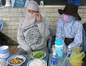 Bà Ngộ (trái) luôn bịt kín khẩu trang. Nữ doanh nhân này chỉ mở ra khi ăn cơm, uống nước trước lều bạt căng ngay cổng biệt thự đại gia thủy sản Diệu Hiền